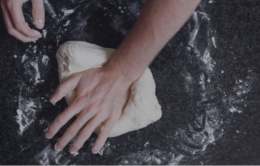 Hand kneads dough on dark counertop
