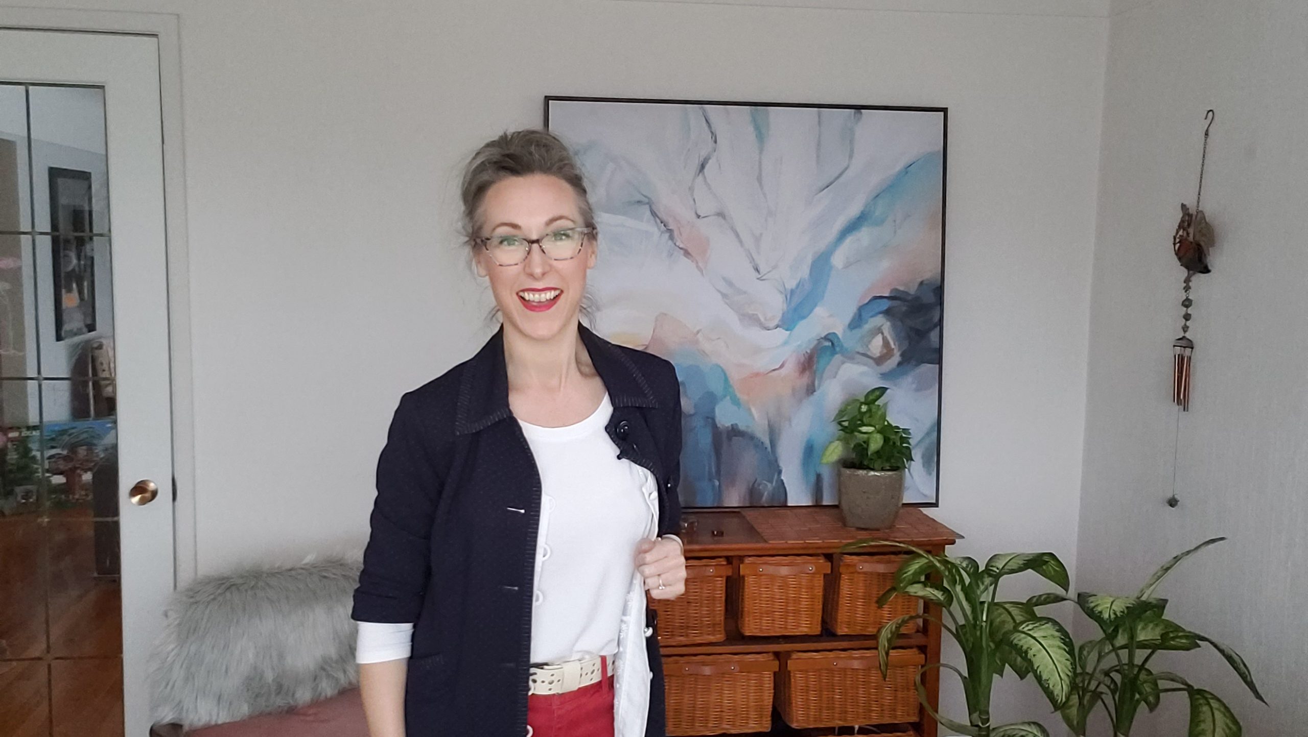 Erin Acton smiles with plants and an abstract painting behind her
